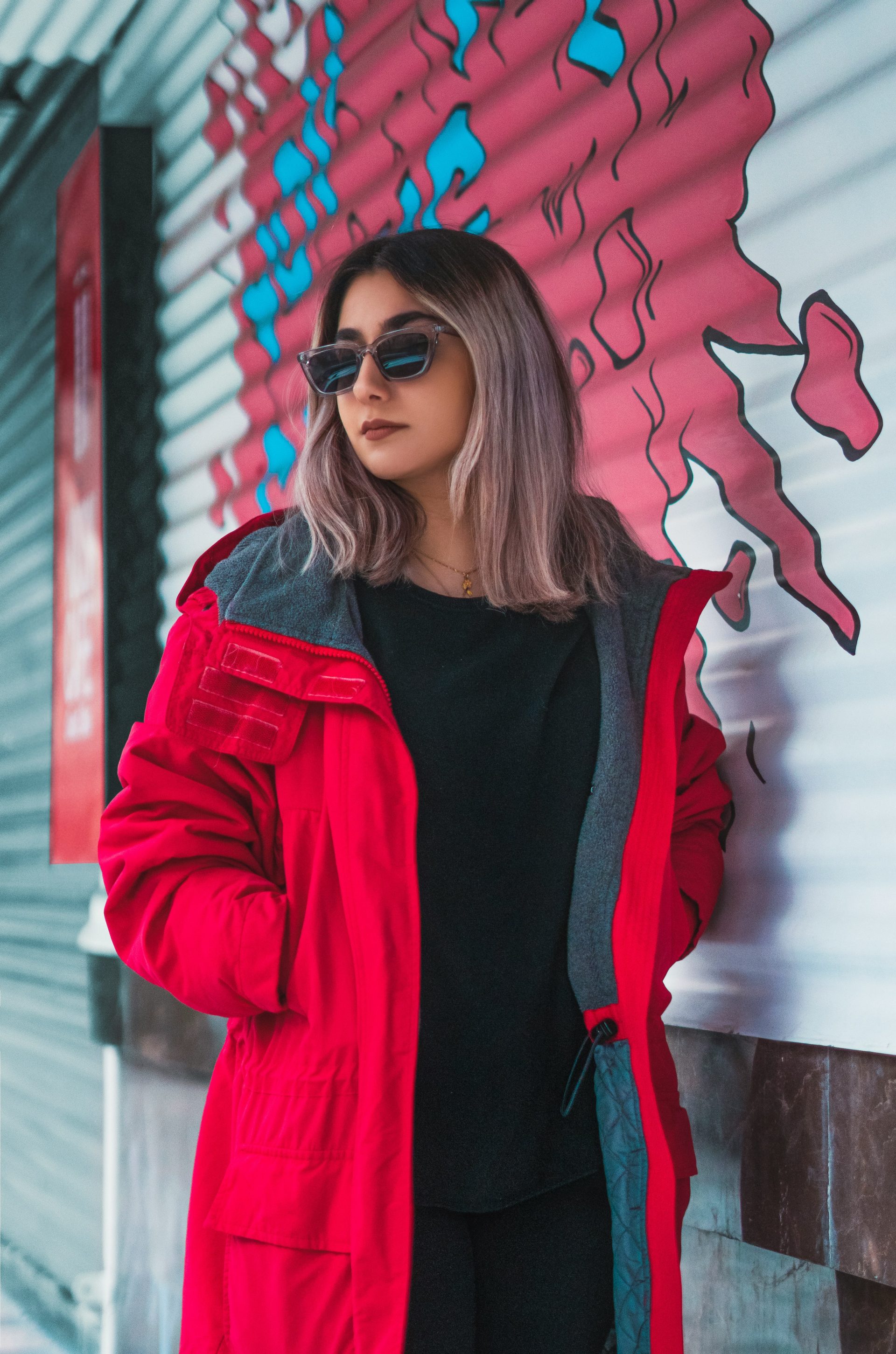a woman in a red coat leaning against a wall